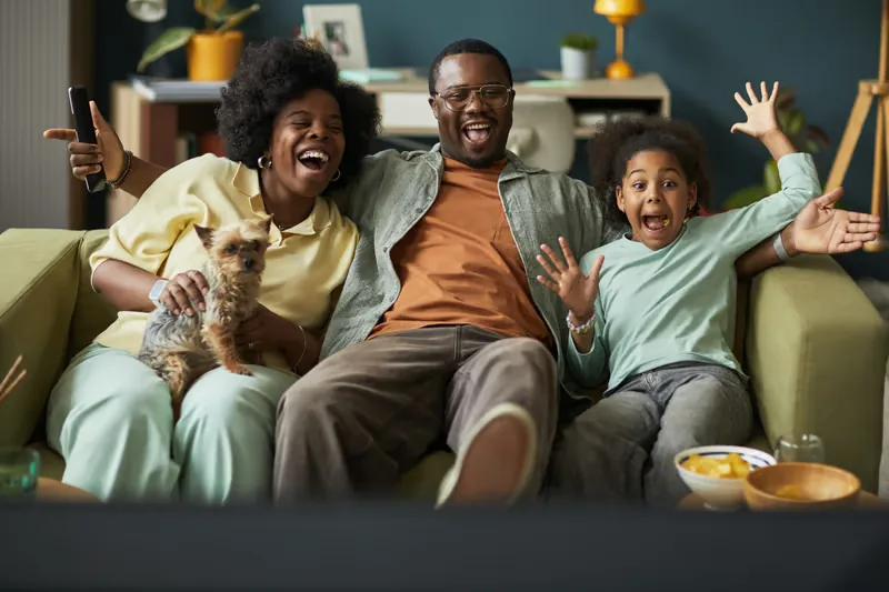 Happy family watching TV after cancelling cable and saving money