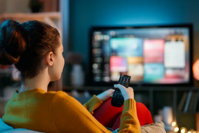 Woman doing an IPTV setup and browsing the streaming interface with a remote